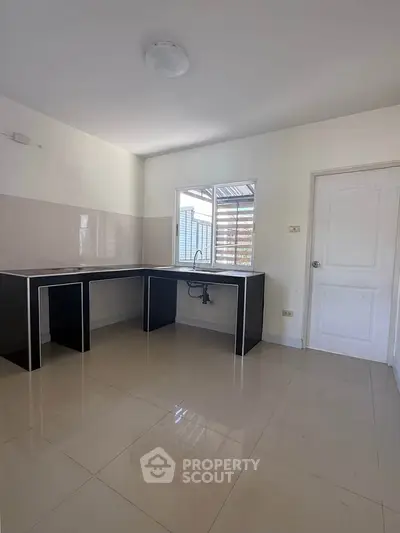 Spacious kitchen with sleek black countertops and ample natural light, perfect for culinary enthusiasts.