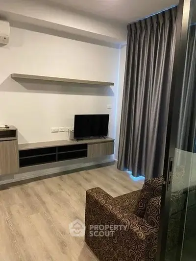 Modern living room with sleek furniture and stylish decor, featuring a mounted TV and elegant curtains.