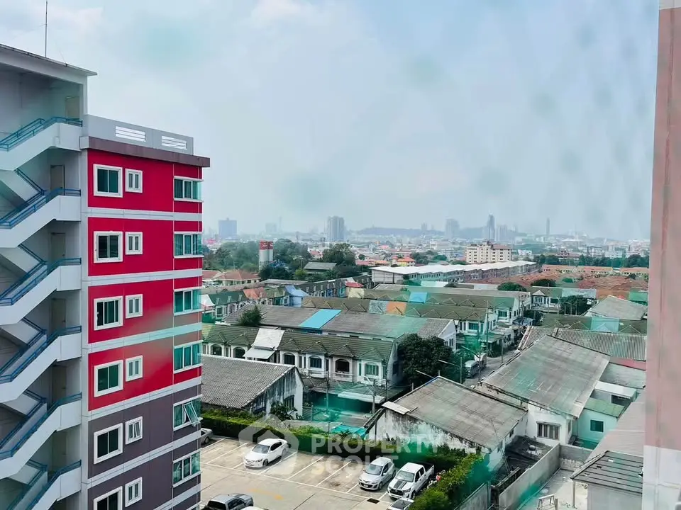 Stunning cityscape view from high-rise building with vibrant red facade and urban skyline.