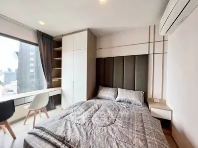 Modern bedroom with city view, featuring stylish furniture and ample natural light.