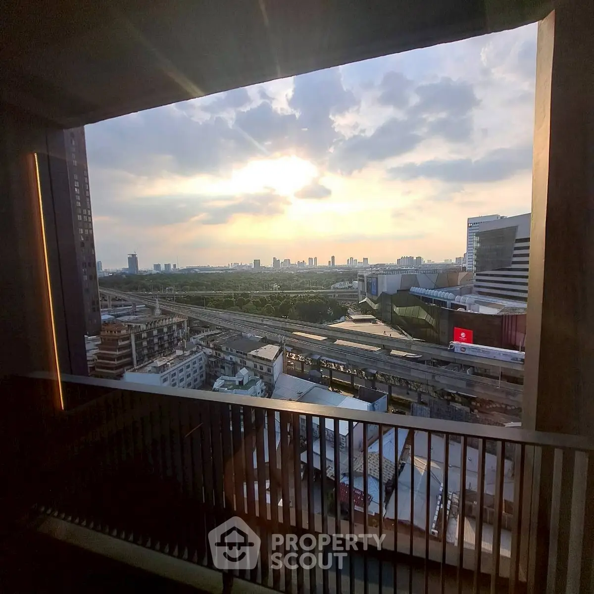 Stunning cityscape view from a high-rise balcony at sunset, showcasing urban skyline and horizon.
