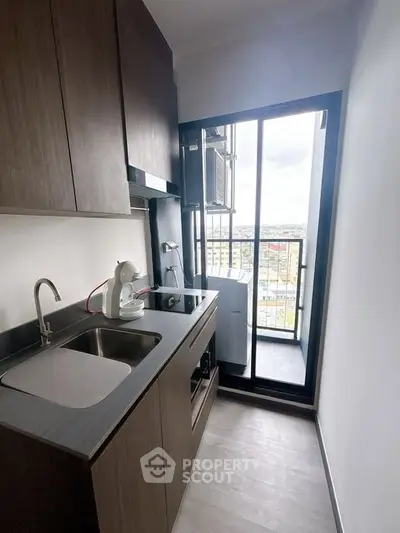 Modern compact kitchen with sleek cabinetry and balcony view, perfect for urban living.