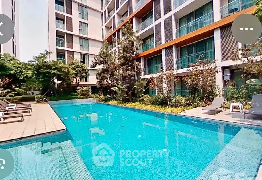 Luxurious apartment complex with a stunning outdoor pool and lush greenery.