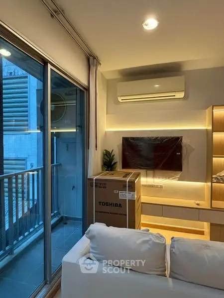 Modern living room with balcony, featuring air conditioning and new Toshiba TV in a sleek urban apartment.