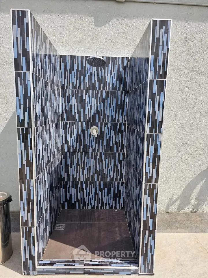 Stylish outdoor shower with modern tile design, perfect for poolside refreshment.