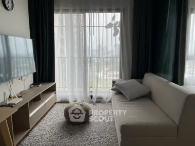 Modern living room with cozy sofa, large TV, and city view through sheer curtains.