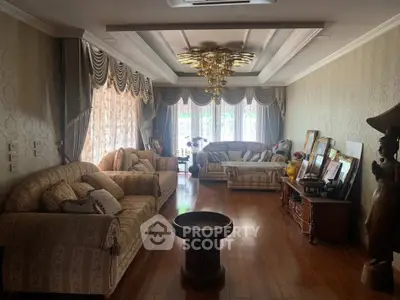 Elegant living room with luxurious sofas, ornate curtains, and wooden flooring.