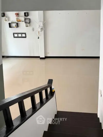 Spacious empty living room with modern staircase and wall shelves