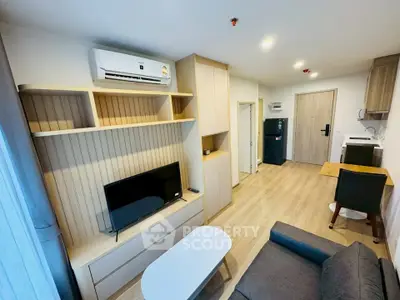 Modern living room with sleek furniture and open layout, featuring a wall-mounted TV and air conditioning.