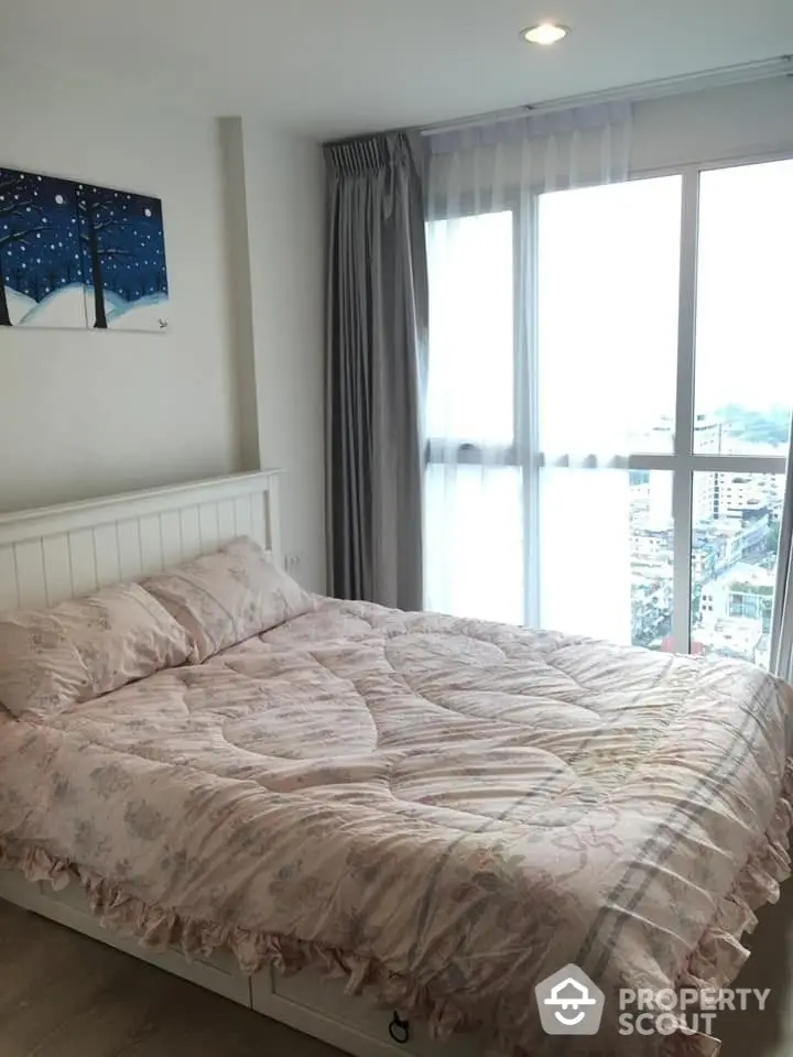 Cozy bedroom with a large window offering a panoramic city view, adorned with a stylish wall art and elegant drapery, perfect for urban living.