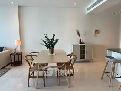 Modern dining area with stylish wooden table and chairs in a bright open-plan living space.