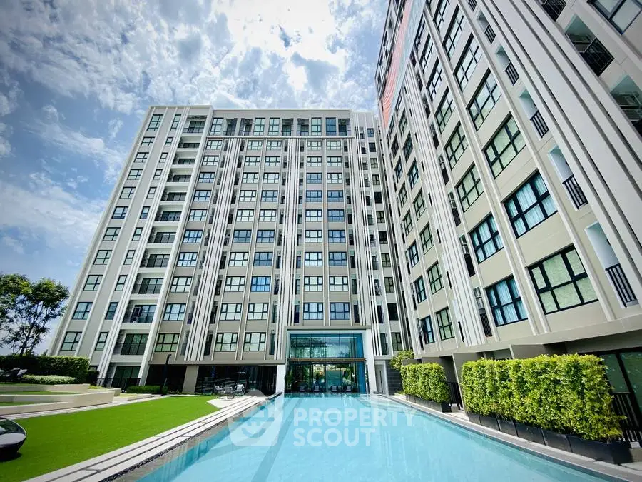 Modern high-rise apartment building with pool and lush greenery