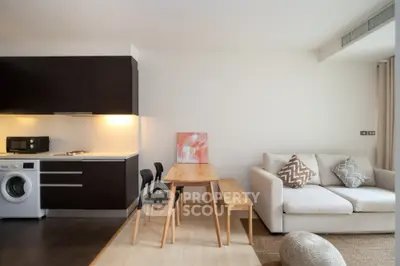 Modern open-plan living room with kitchen, featuring sleek furniture and integrated appliances.
