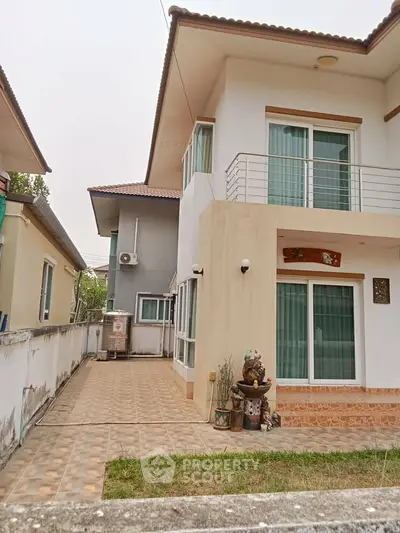 Charming two-story house with balcony and spacious outdoor area, perfect for family living.