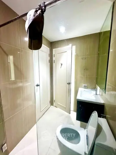 Modern bathroom with sleek fixtures and neutral tones, featuring a glass shower and contemporary design.