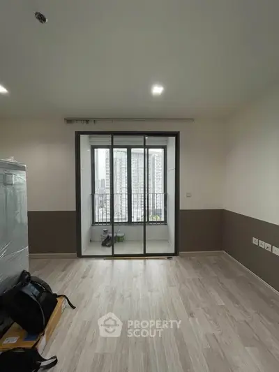 Spacious modern living room with sliding glass doors leading to a balcony with city views.