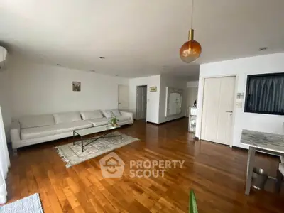 Spacious living room with wooden flooring and modern decor in a stylish apartment.