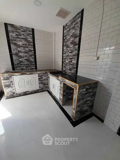 Modern kitchen with sleek black countertops and stylish tile backsplash