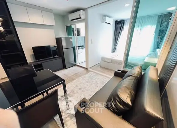 Modern living room with sleek furniture and open view to bedroom