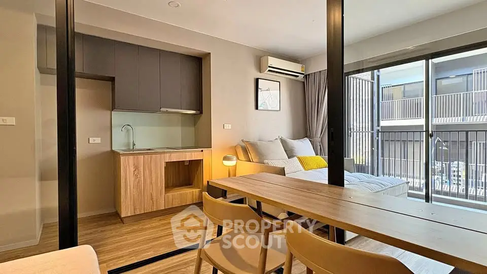 Modern studio apartment with open layout, featuring a cozy living area, compact kitchen, and large windows for natural light.