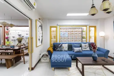 Stylish living room with modern decor and open dining area, featuring a cozy blue sectional sofa.