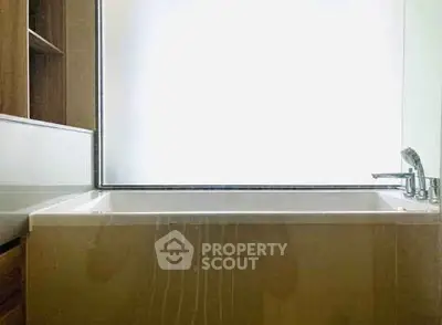 Modern bathroom with sleek bathtub and frosted glass window