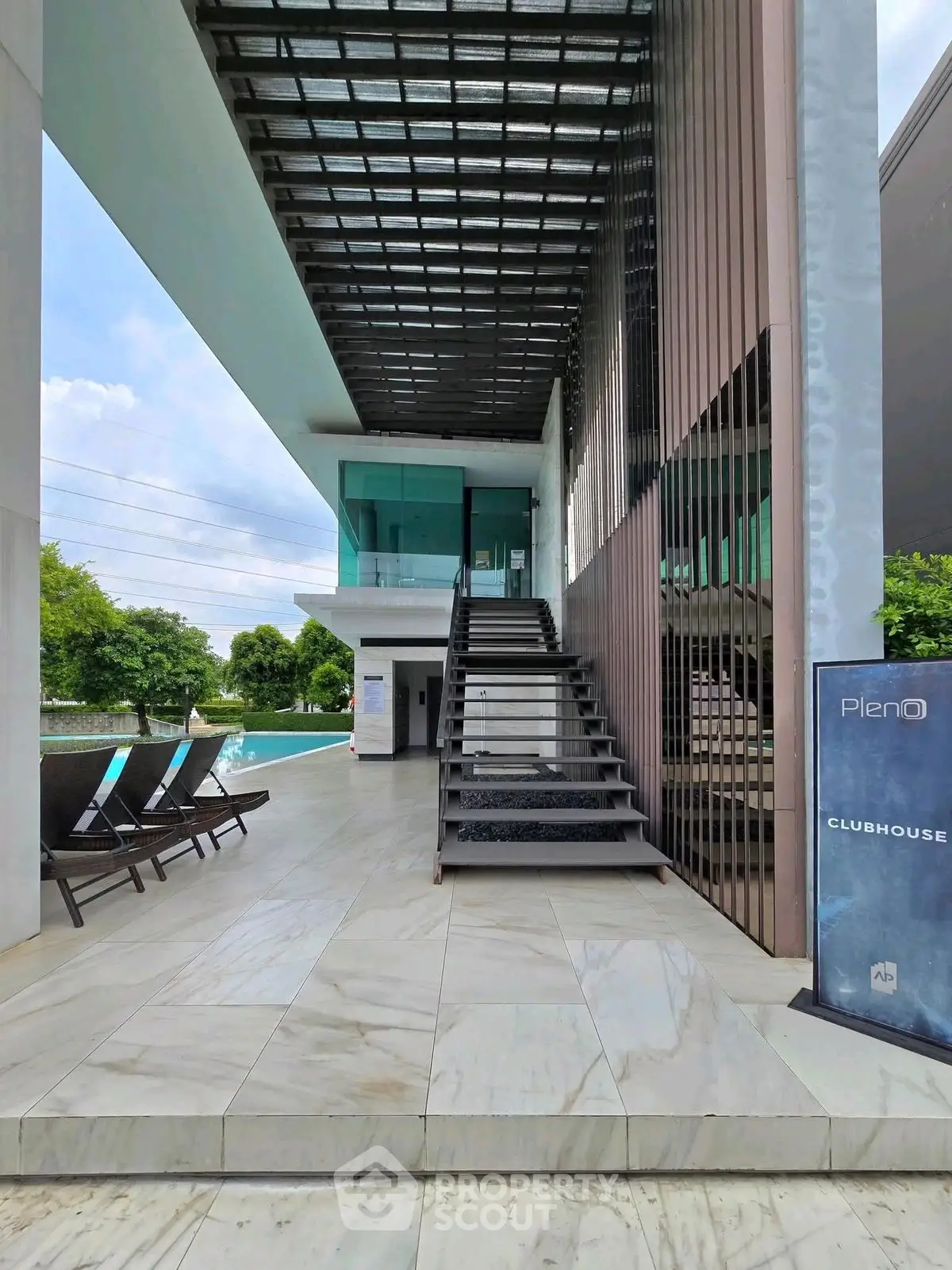 Modern clubhouse entrance with poolside view and sleek architectural design.