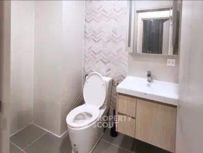 Modern bathroom with sleek design and stylish tiles, featuring a contemporary toilet and vanity unit.