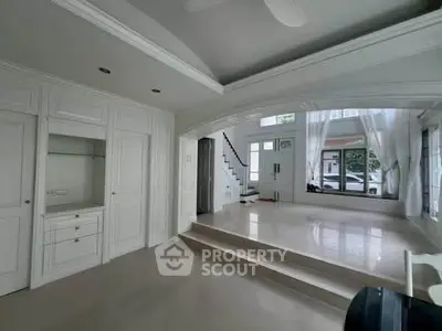 Spacious modern living room with elegant white interiors and large windows.