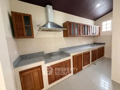 Spacious kitchen with wooden cabinets and modern range hood