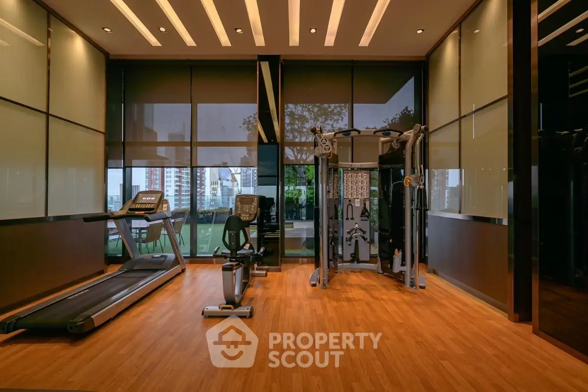 Luxurious gym with modern equipment and city view in upscale real estate property.