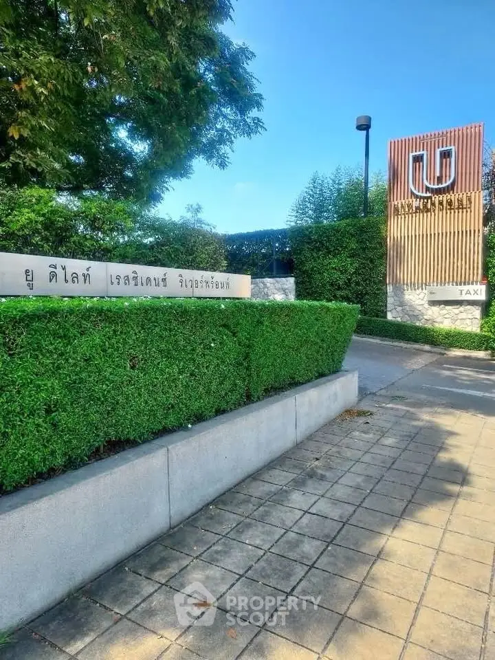 Modern residential entrance with lush greenery and stylish signage