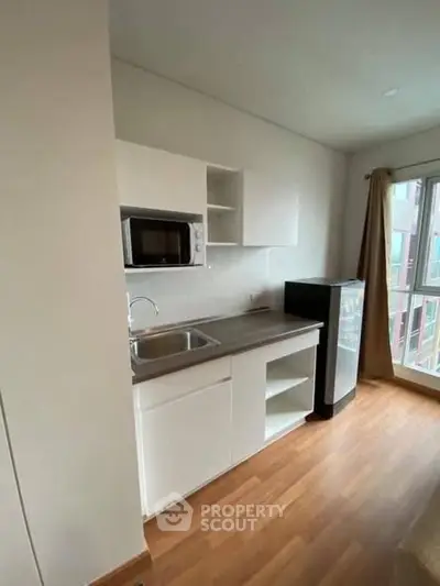 Modern compact kitchen with sleek cabinetry and appliances in a bright apartment.