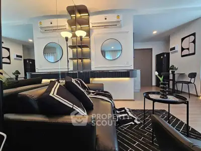Modern living room with stylish black leather sofa, geometric decor, and mirrored wall accents.