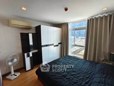 Modern bedroom with large window and stylish furniture in urban apartment
