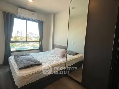 Modern bedroom with large window and mirrored wardrobe, offering a cozy and bright atmosphere.