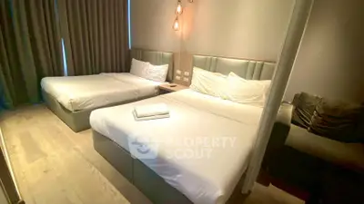 Spacious modern bedroom with two beds and elegant lighting in a cozy apartment.