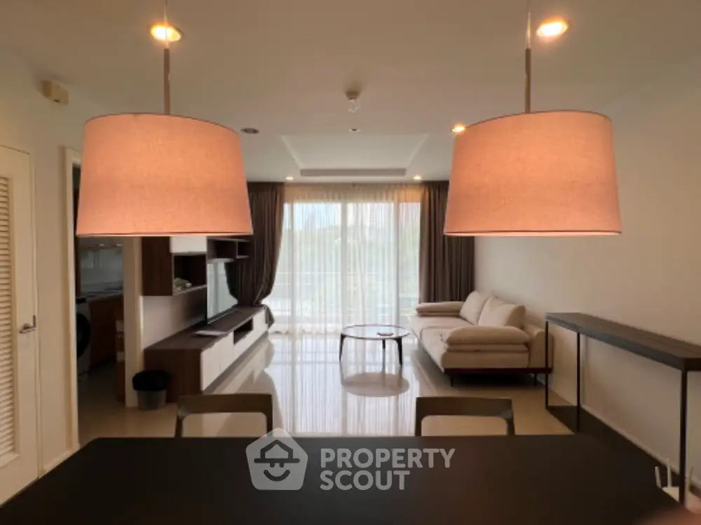 Modern living room with stylish lighting and elegant furniture, featuring a spacious layout and large windows.