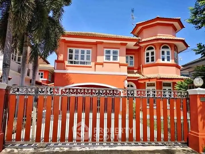 Stunning two-story orange house with unique architectural design and gated entrance.