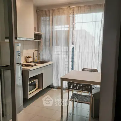 Cozy kitchen with dining area and natural light through sheer curtains.
