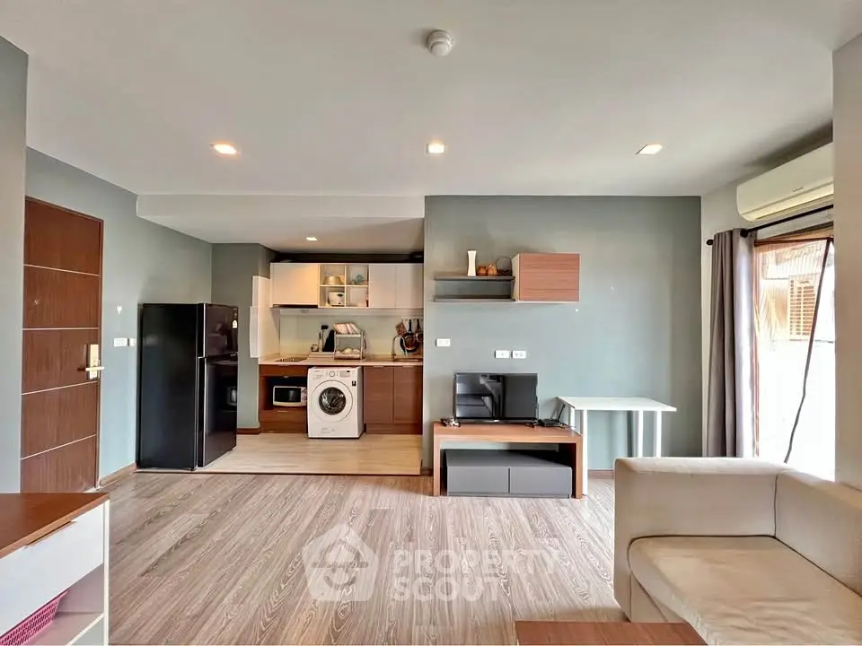 Modern open-plan living room with kitchen featuring washing machine and fridge, ideal for urban living.