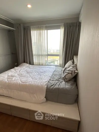 Cozy bedroom with city view, featuring a comfortable bed and large window for natural light.