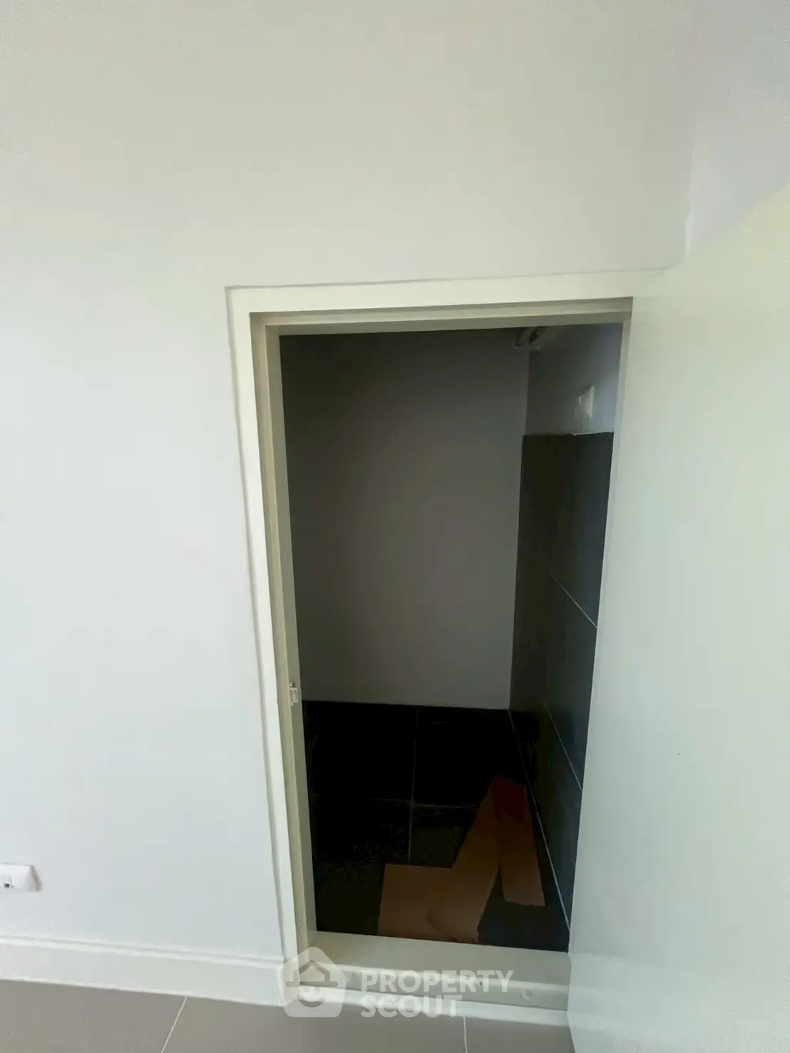 Small storage room with dark tiles and white walls, ideal for compact spaces.