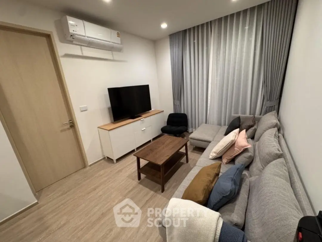 Modern living room with cozy gray sofa, flat-screen TV, and stylish decor.