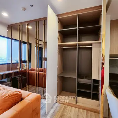Modern living room with open shelving and mirrored wall, featuring a cozy orange sofa and wooden flooring.