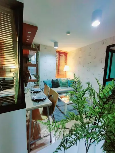 Cozy and inviting open-layout living space with modern furnishings, warm lighting, and a touch of greenery, perfect for urban living.