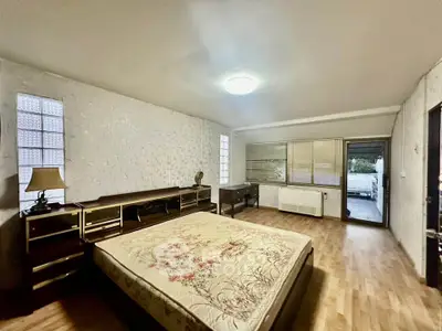 Spacious bedroom with wooden flooring and large windows for natural light.