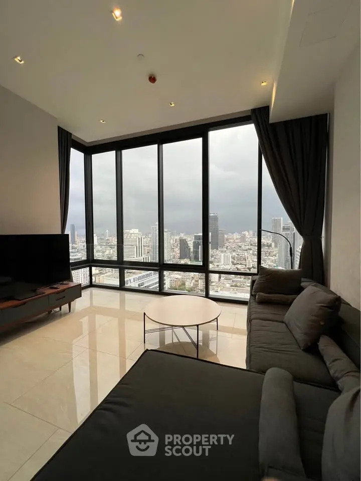 Luxurious living room with panoramic city views and modern furnishings in a high-rise apartment.