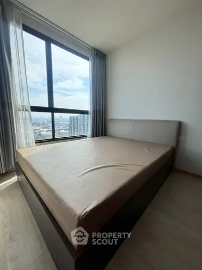 Modern bedroom with large window offering stunning city view and natural light.