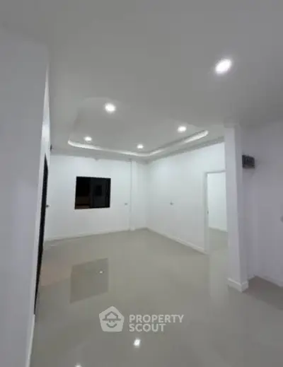 Spacious modern living room with sleek ceiling design and glossy floor tiles.